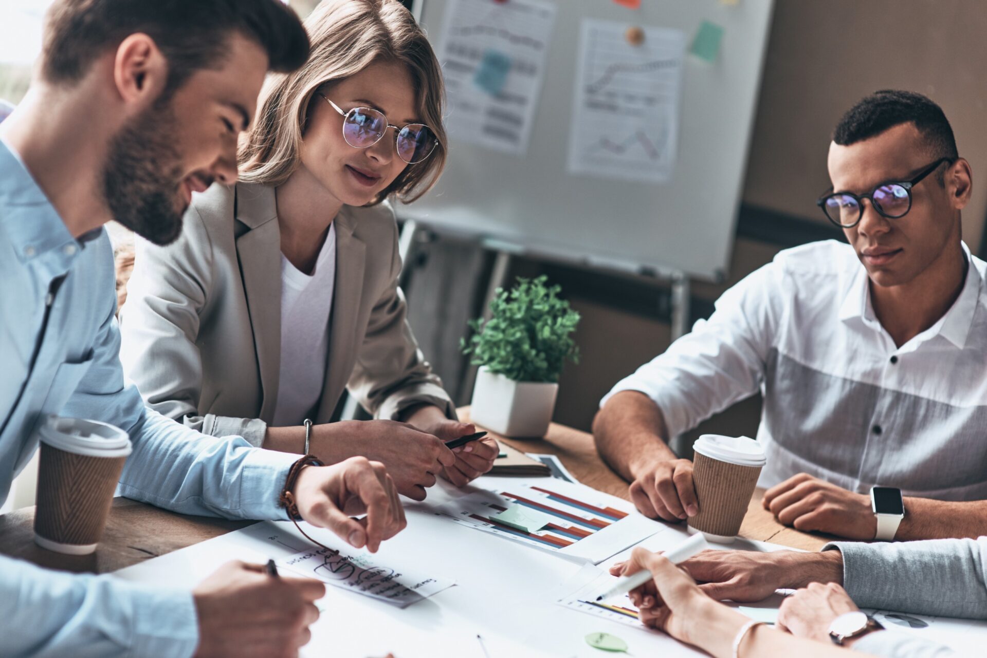 Top view of modern people in smart casual wear working using blueprint while sitting in the creative office<br />
