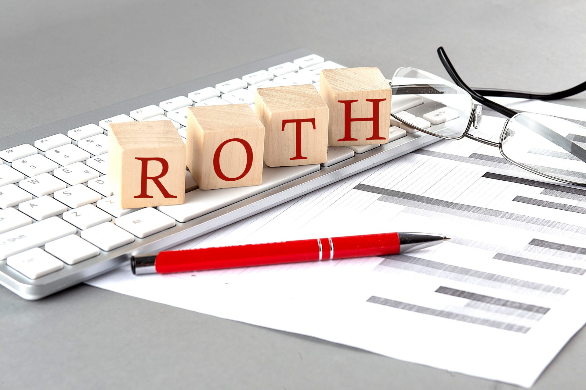 ROTH written on a wooden cube on the keyboard with chart on grey background